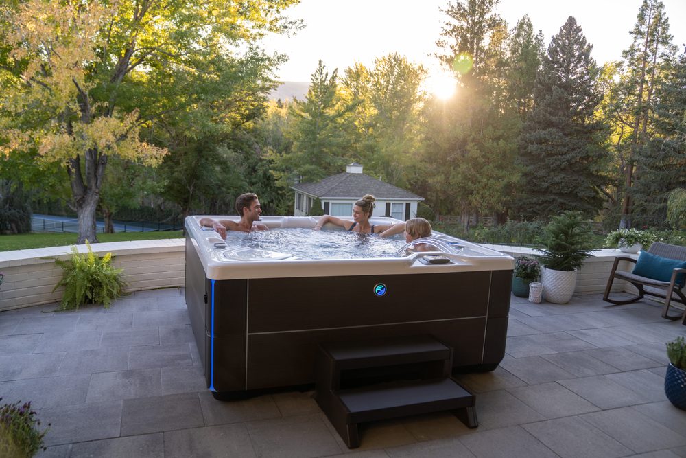 Family enjoying a Hot Spring Highlife hot tub at sunset