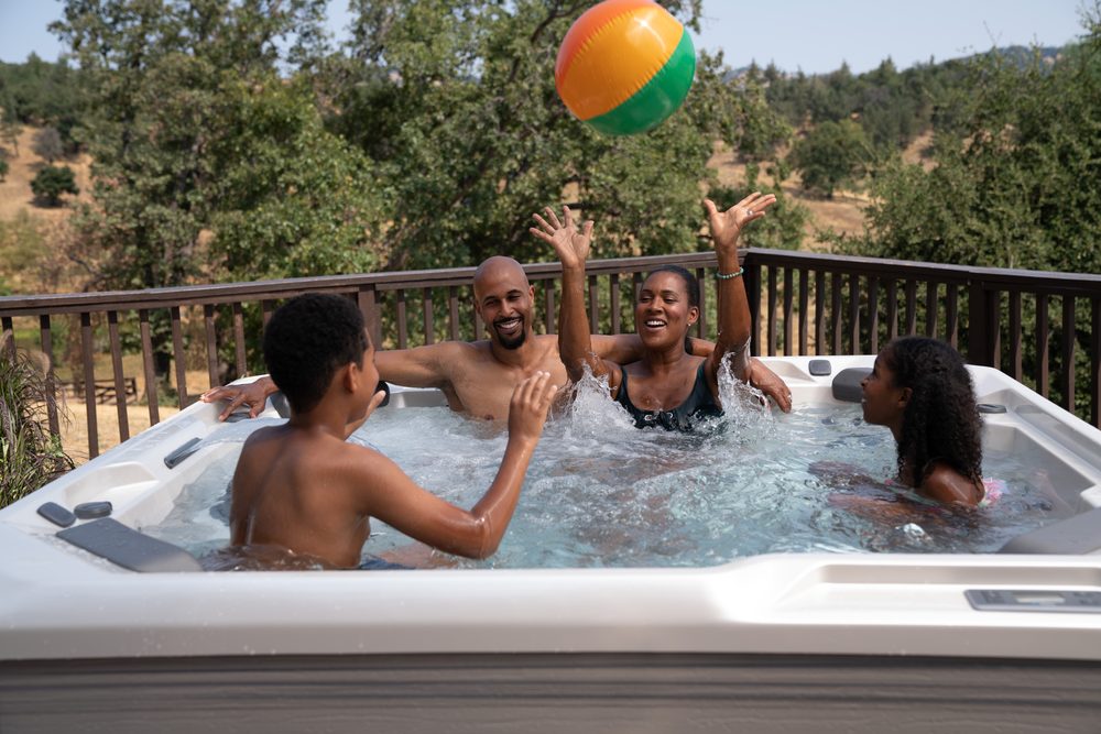 Family playing in a Hot Spring Hot Spot hot tub on a sunny deck