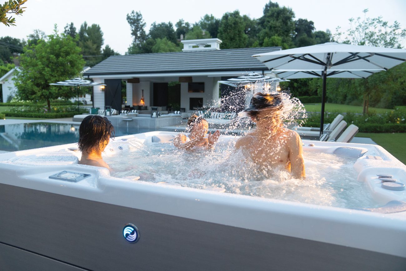 Family enjoying a Hot Spring Highlife Grandee hot tub at sunset