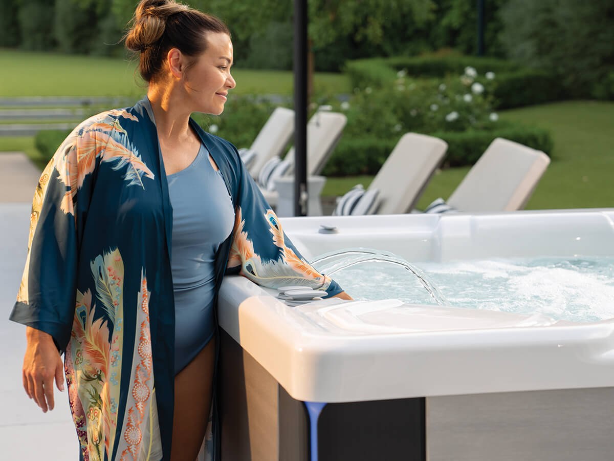 Woman testing the water of a Hot Spring Highlife Grandee hot tub