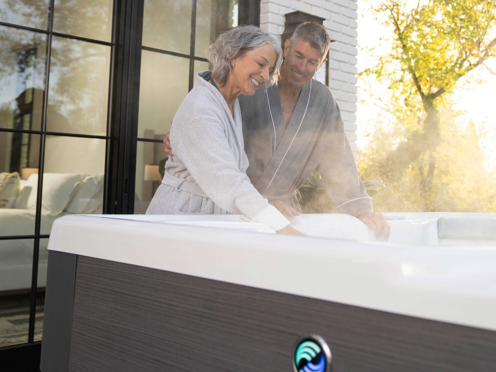 Couple testing the warm water of a Hot Spring Highlife hot tub at home